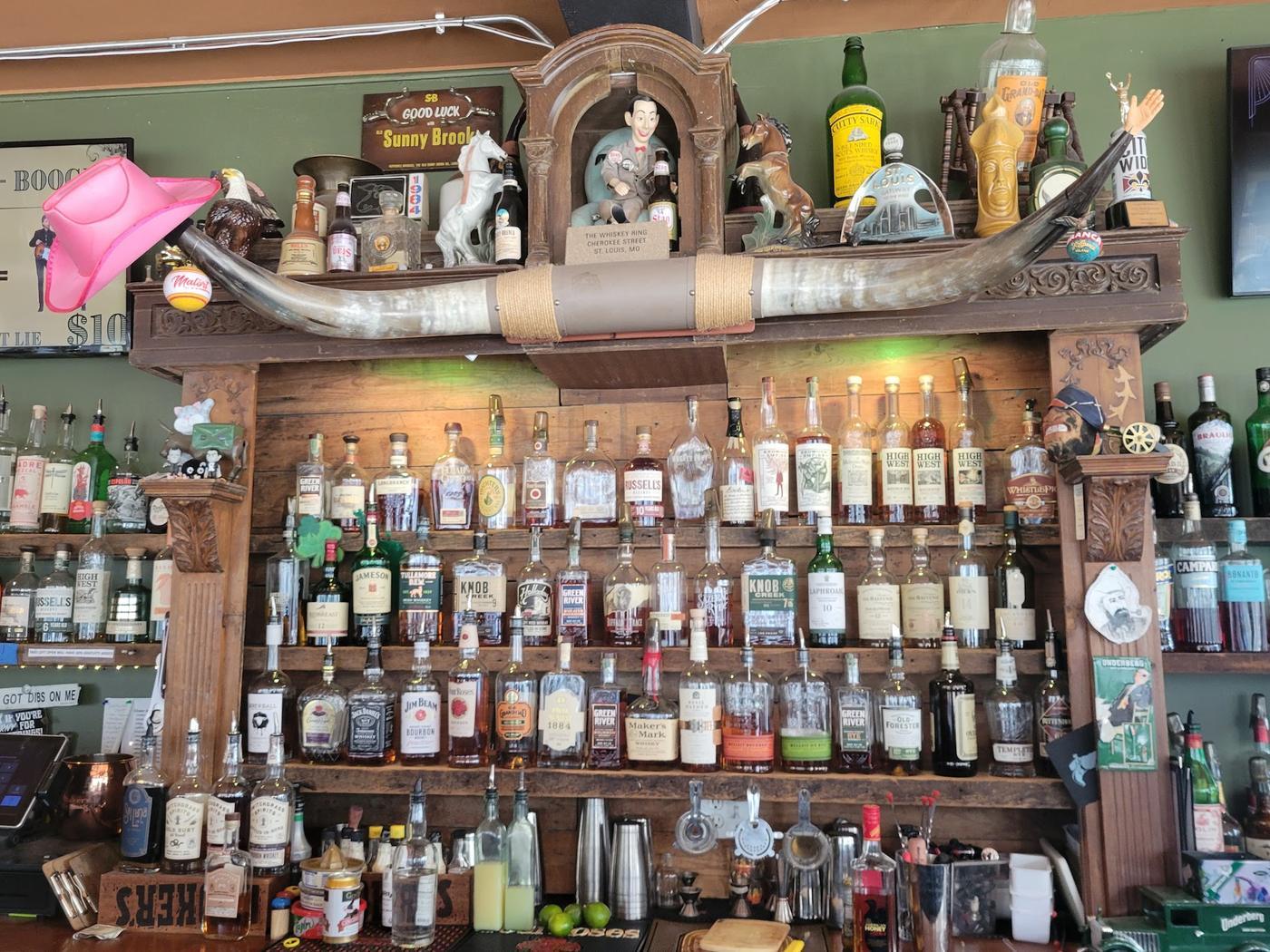 The back bar at The Whiskey Ring, shelves of whiskey on reclaimed timber under mounted longhorns