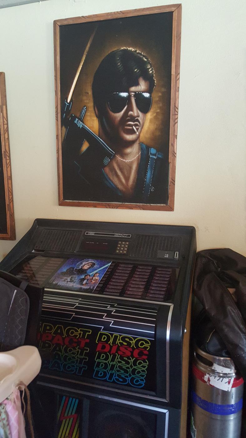 A velvet painting hanging above a vintage jukebox