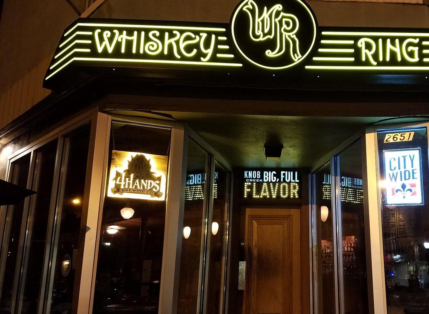 The Whiskey Ring's green neon sign lit at night above the door at 2651 Cherokee Street